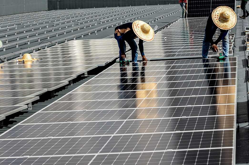 People with straw hats working on a solar panel